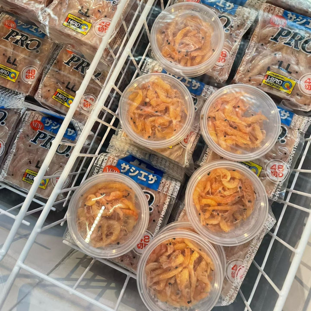 A retail freezer display showing packaged food items, including several clear plastic cups filled with orange-brown shredded contents and multiple packages labeled PRO and シリタイー behind them.